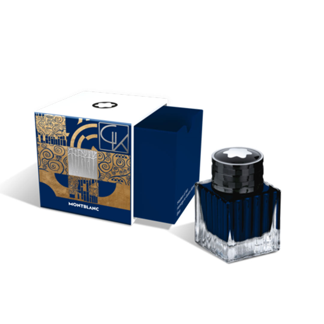 A bottle of Montblanc Masters of Art Homage to Gustav Klimt Blue 50ml Ink sits next to its box. The clear glass bottle with a black cap complements the box, which is adorned with abstract blue and gold designs as part of Montblanc's Special Edition celebrating Masters of Art.