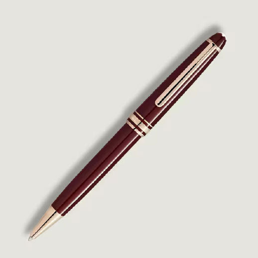 A Montblanc Meisterstück Burgundy Red Classique Ballpoint Pen with gold fittings and a clip is placed diagonally on a plain light gray background.