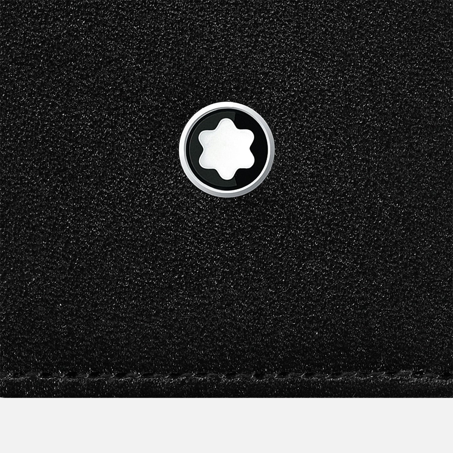 A close-up of the textured black leather surface of the Montblanc Meisterstück Black Leather Pen Pouch highlights a silver and black circular Montblanc emblem at its center, with a star-like shape within the emblem, capturing the elegance typical of Montblanc's design.