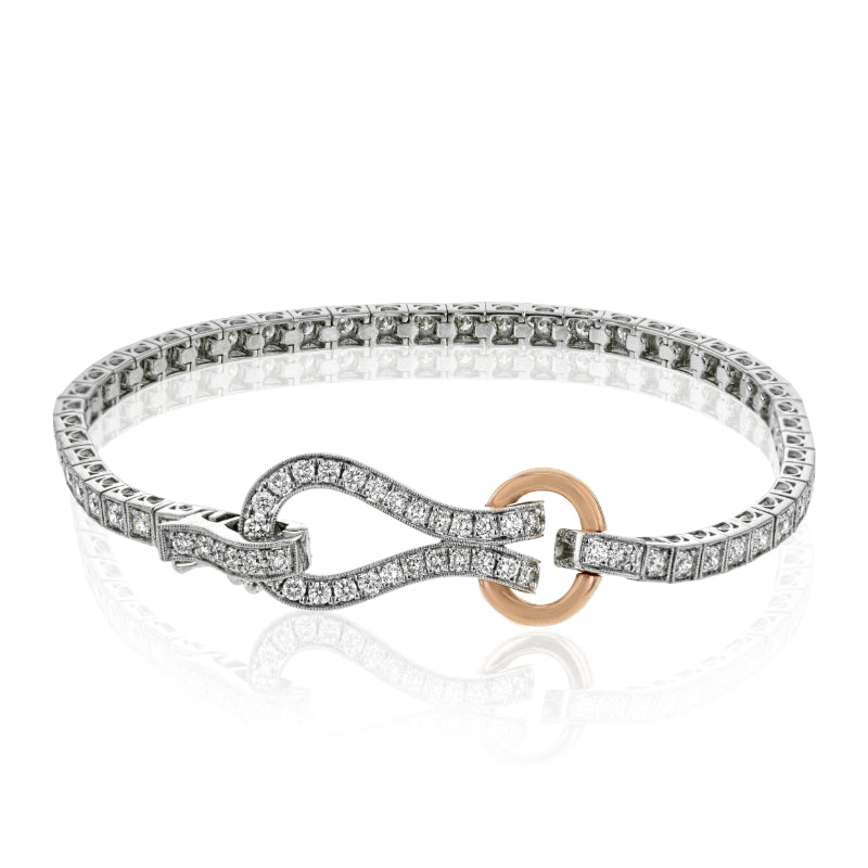 Introducing the Simon G. 18K White and Rose Gold Diamond Buckle Bracelet, a stunning piece featuring round diamonds in a diamond-studded design with an infinity-shaped clasp. Accentuated by a small gold circle, this bracelet offers an elegant and intricate pattern along its entire length, providing a timeless sophistication characteristic of the Simon G brand.