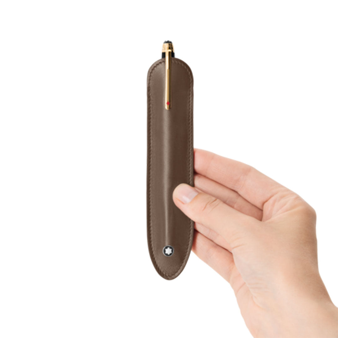 A hand holds a Montblanc Meisterstück Brown Leather Pen Pouch, showcasing a golden pen inside, against a plain white background.