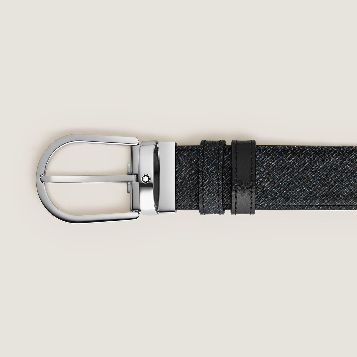 A close-up of the Montblanc Horseshoe Buckle 35mm Reversible Tweed Blue and Black Leather Belt displayed flat on a light beige background.
