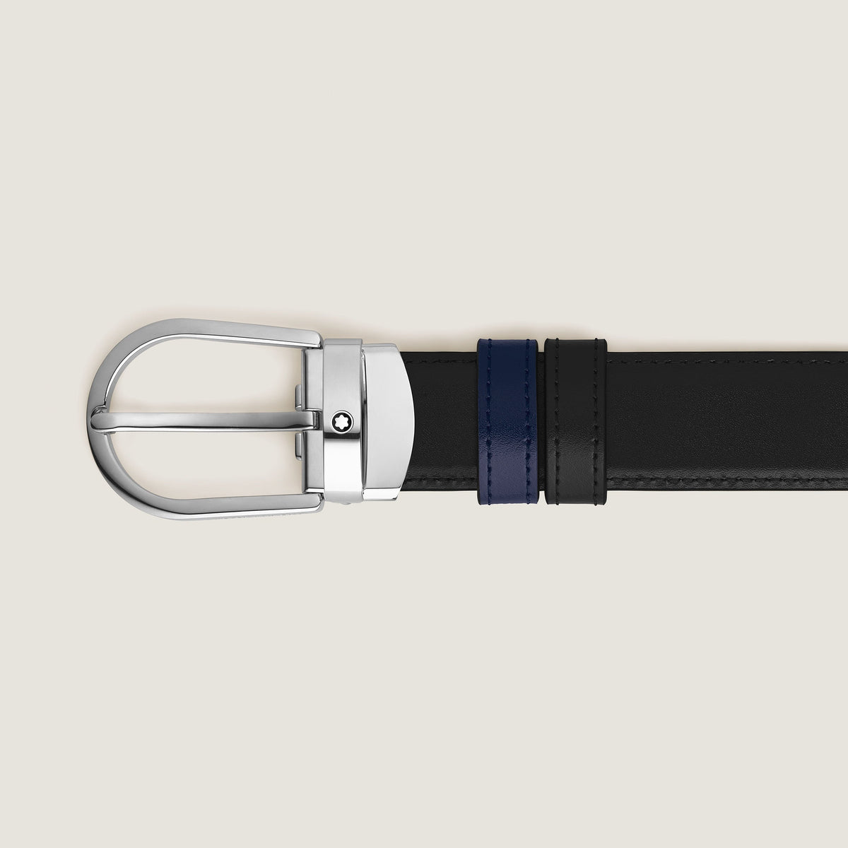 The Montblanc Horseshoe Buckle 30mm Reversible Black and Ink Blue Leather Belt is shown horizontally on a light beige background.