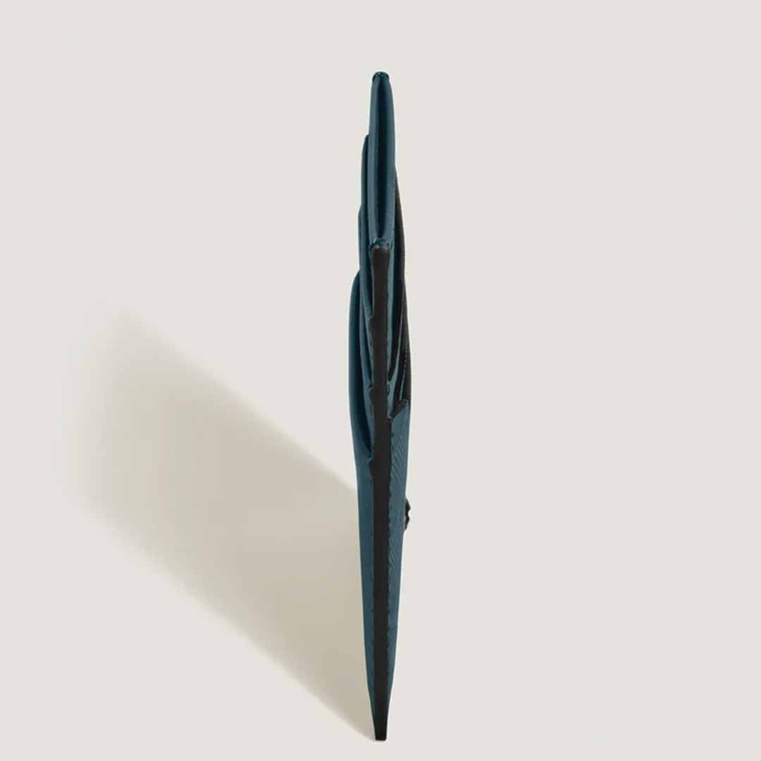 A side view of the Montblanc Extreme 3.0 6cc leather card holder in a sleek, dark green hue against a light background, casting a soft shadow.