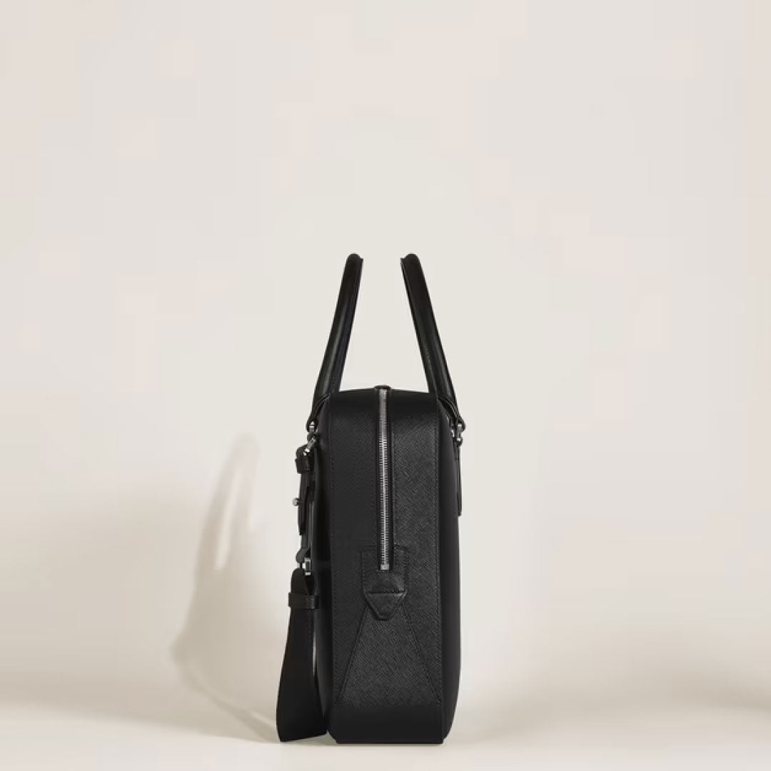 Side view of the Montblanc Sartorial Medium Leather Document Case Bag in sleek black saffiano leather, featuring two handles, a shoulder strap, and a top zipper. The minimalistic Montblanc bag is set against a plain, light background.
