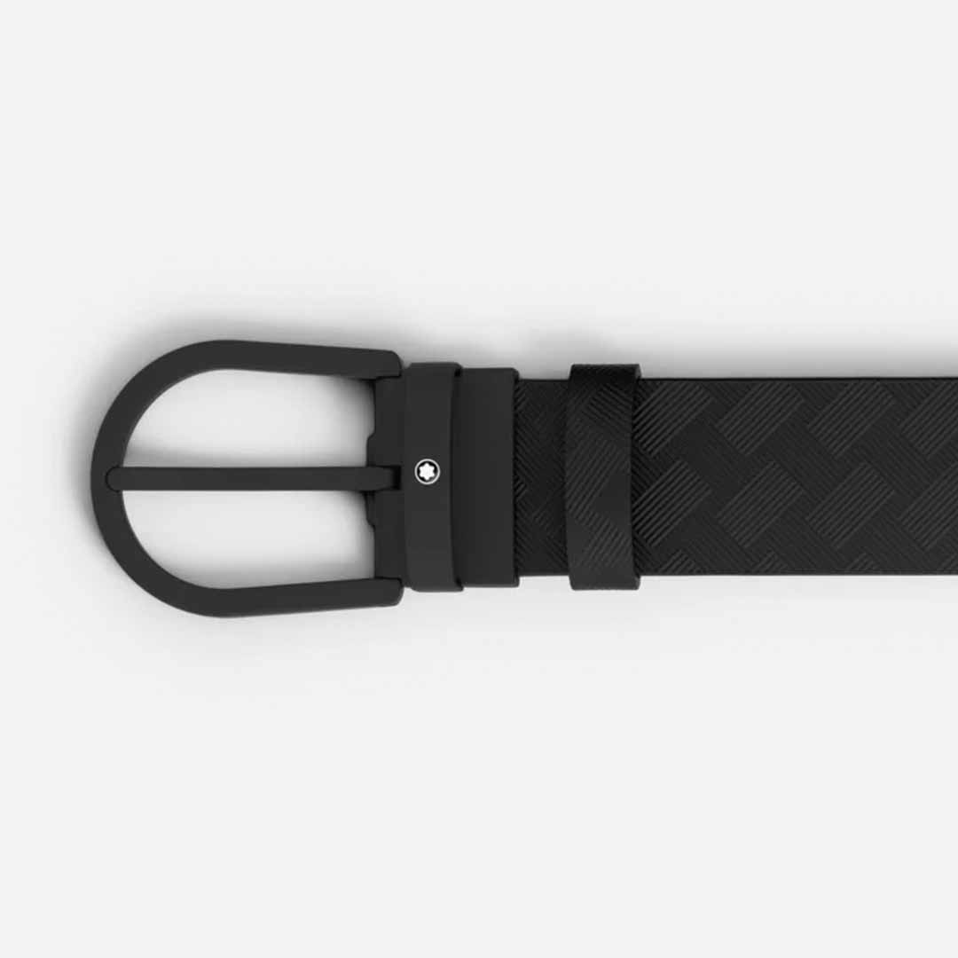 A close-up of the Montblanc Horseshoe 35mm Leather Belt, highlighting its black leather with a matte black buckle and subtle textured pattern. The belt elegantly features the Montblanc emblem and secures with a single metal rivet against a plain white background.