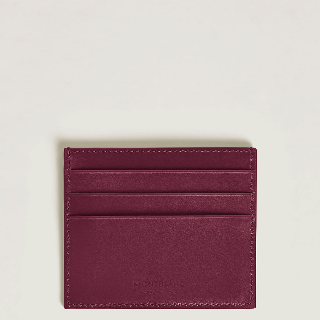 The Montblanc Meisterstuck 6CC Card Holder in burgundy cassis deep shine leather offers three credit card slots and features a subtly embossed Montblanc logo on the front, set against a clean white backdrop.
