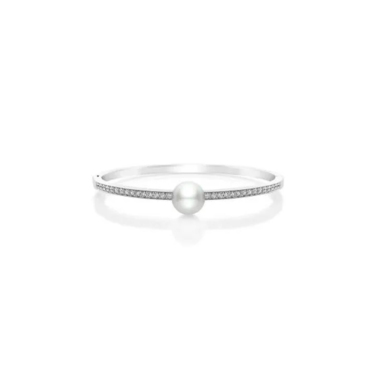 The Mikimoto 18K White Gold Diamond with White South Sea Pearl Bangle showcases a minimalist design, featuring a central white pearl and small round diamonds on one side, elegantly set against a white background.