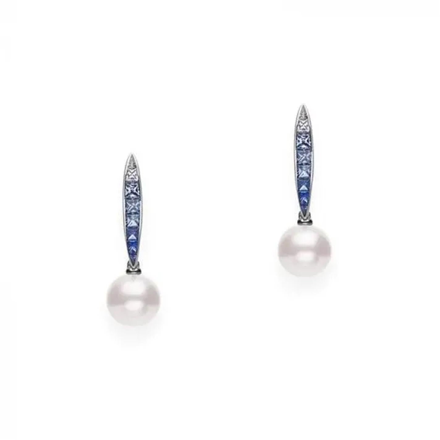 The Mikimoto Ocean Collection 18K White Gold Sapphire with Akoya Cultured Pearl Drop Earrings showcases elegant pearl drops featuring Akoya cultured pearls in vertical settings, adorned with small blue sapphires, all presented against a plain white background.