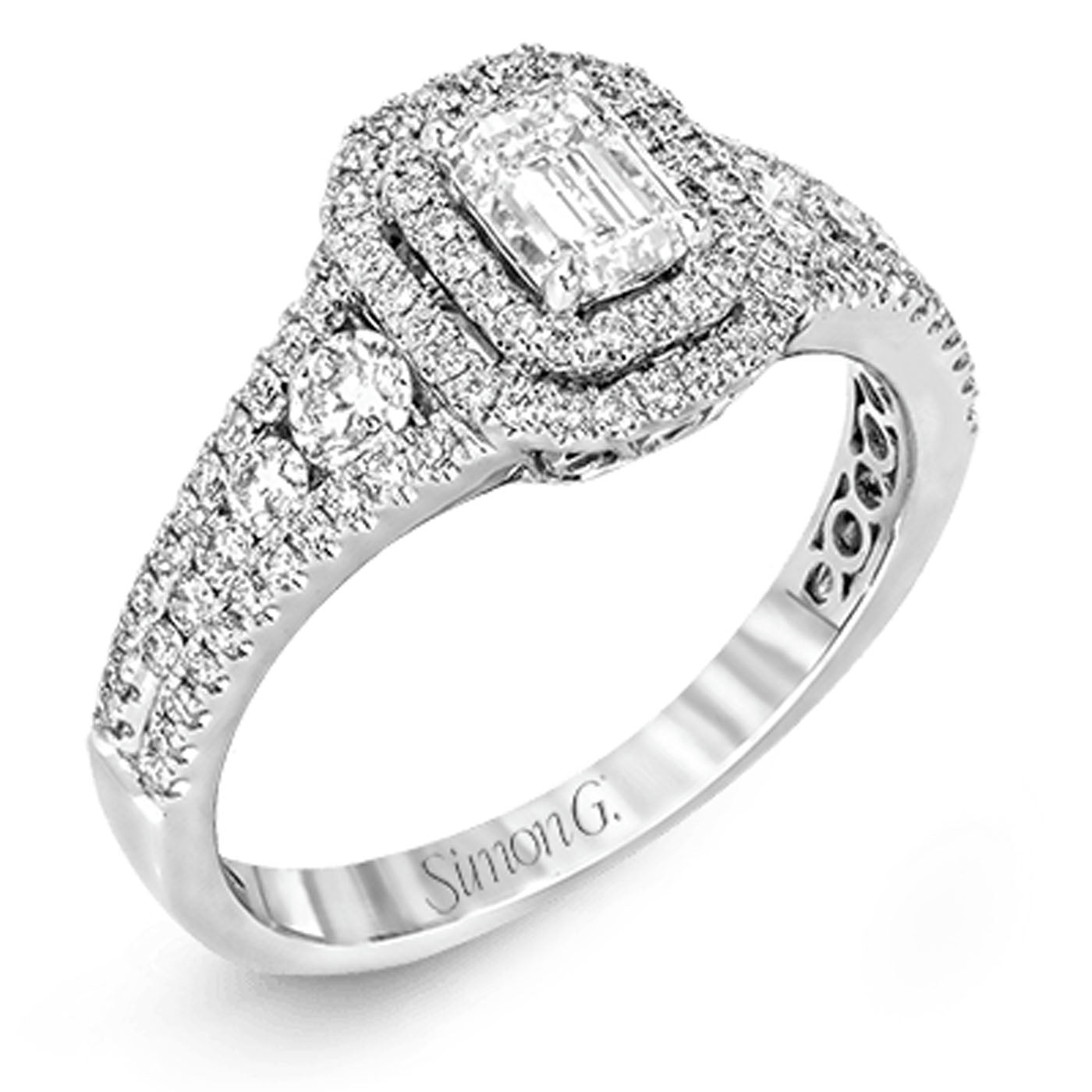 The Simon G. 18K White Gold Emerald Diamond Ring features an elegant emerald diamond as the centerpiece, flanked by round cut diamonds on the band. This stunning ring showcases intricate detailing and shimmering gemstones, embodying the sophistication of Simon G design.