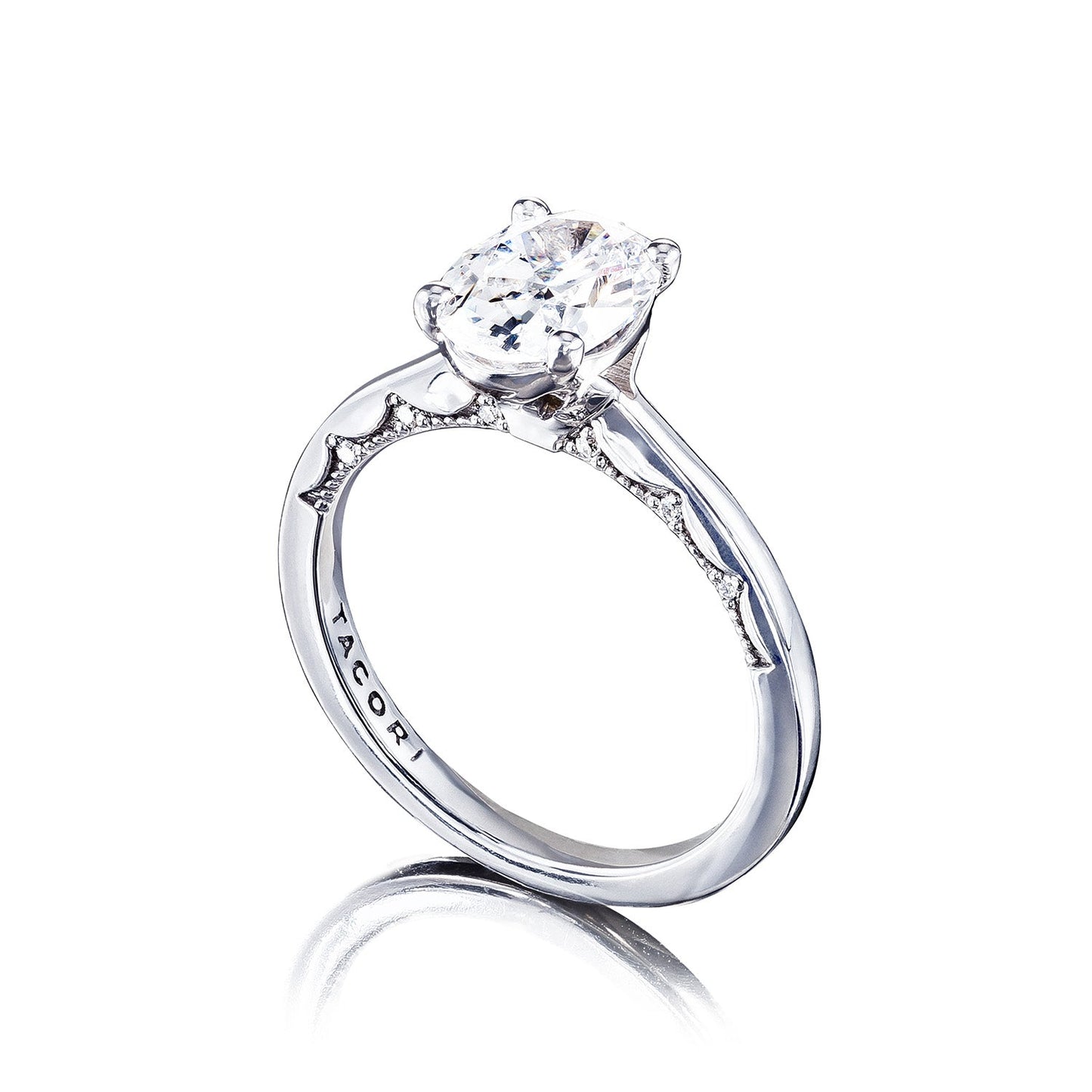 A 14K white gold engagement ring featuring a large oval diamond solitaire set on an intricately detailed band with diamond accents showcases a reflective finish. The Tacori Coastal Crescent design elegantly displays the allure of its brand name "Tacori" engraved on the side.