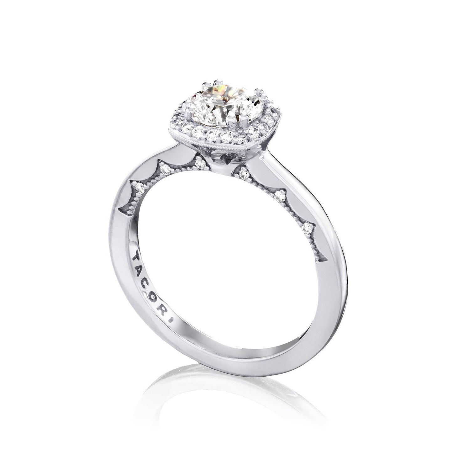 The Tacori Coastal Crescent engagement ring in 14K white gold features a central large round brilliant diamond, surrounded by a halo of smaller diamonds. The band is intricately detailed and engraved with "TACORI," embodying elegance and timeless beauty.