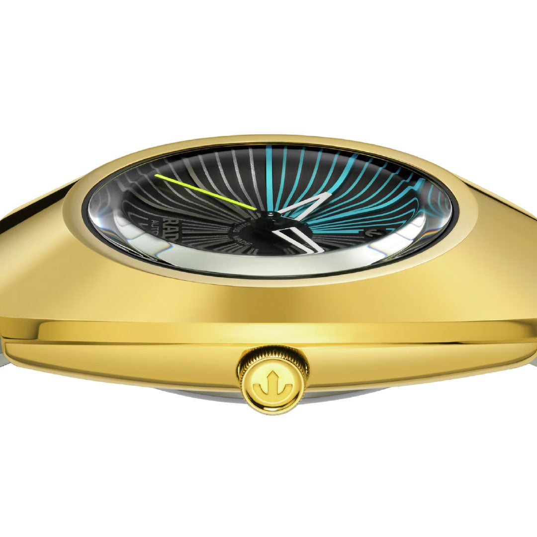 A close-up side view of the RADO Diastar Original X Tej Chauhan Special Edition Automatic 38mm Watch shows a gold case, patterned black, white, and blue dial, yellow second hand, and anchor crown—highlighting Swiss craftsmanship and smooth curves.