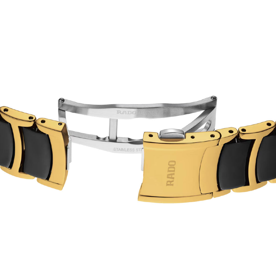 A close-up of the RADO Centrix Diamonds Quartz 39.5mm watch bracelet with a deployment clasp, featuring yellow gold PVD-coated stainless steel, black ceramic links, a silver inner mechanism, and a black sunray dial.