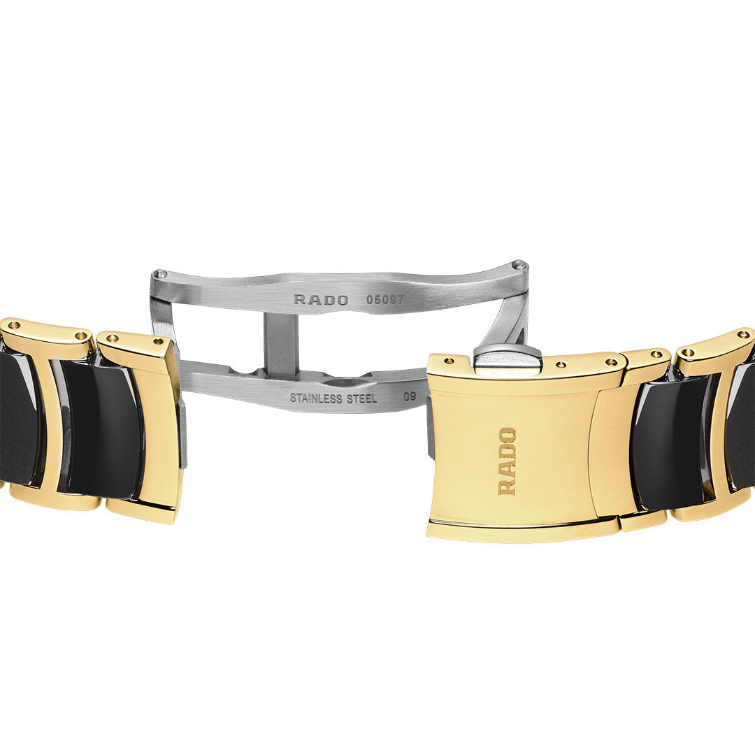 A close-up of the RADO Centrix Moonphase Quartz 35mm Watch bracelet, showing its gold and black two-tone links plus a stainless steel deployment clasp engraved with "RADO" and "STAINLESS STEEL.
