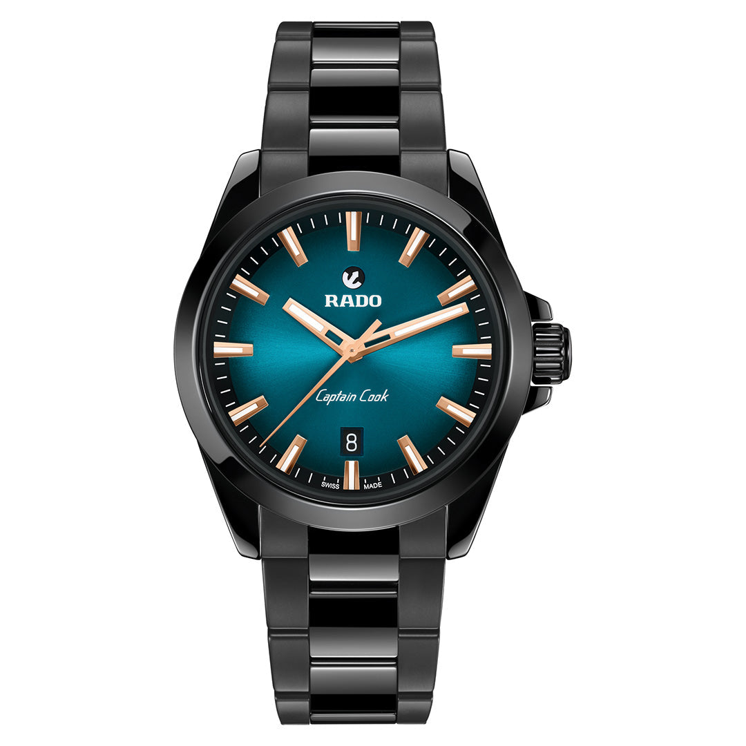 The RADO Captain Cook Discover Automatic 40.7mm Watch features a black metal band, teal blue gradient dial, rose gold hour markers, date at 6 o’clock, and “Captain Cook” above the date.