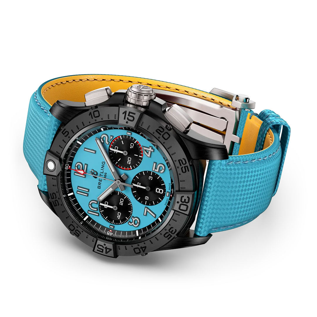The Breitling Avenger B01 Chronograph 42 Night Mission is a luxury aviation watch with a black bezel, turquoise dial, three black subdials, and a turquoise textured strap with yellow underside, shown on a white background.