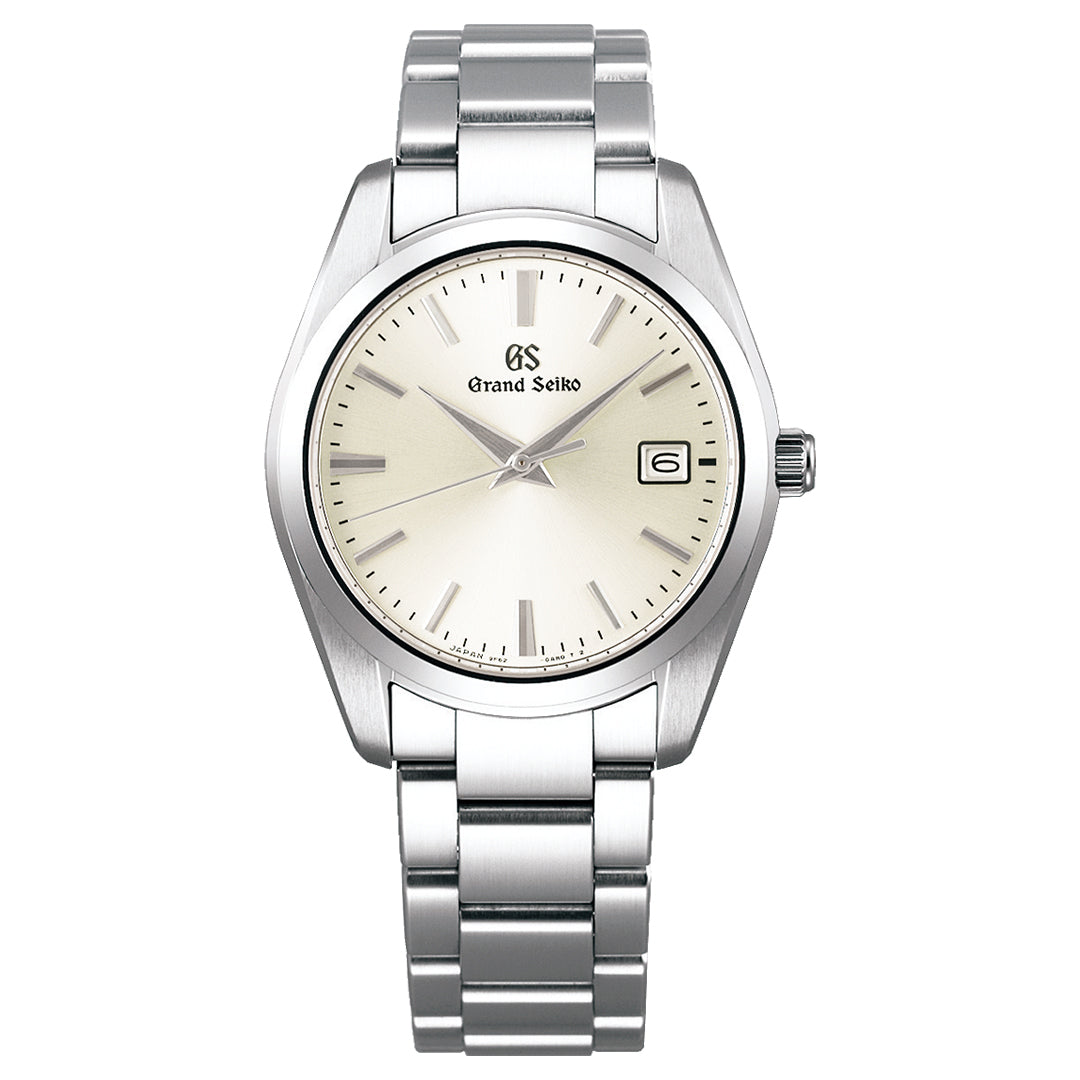 The Grand Seiko Heritage Collection Quartz 37mm Watch features a silver metallic strap, white dial, simple hour markers, and hands. It has a date window at 3 o'clock with the elegant Grand Seiko logo below 12 o'clock.