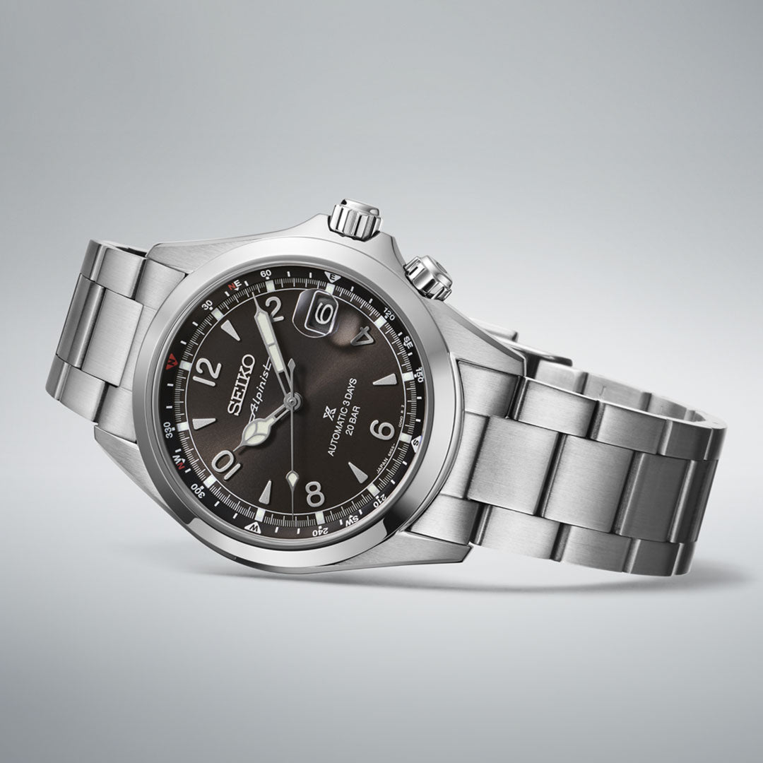 The Seiko Prospex Land Alpinist Automatic 39.5mm watch features a stainless steel case, black dial, silver markers, date window at 3 o’clock, and metal bracelet, shown against a light gray background.