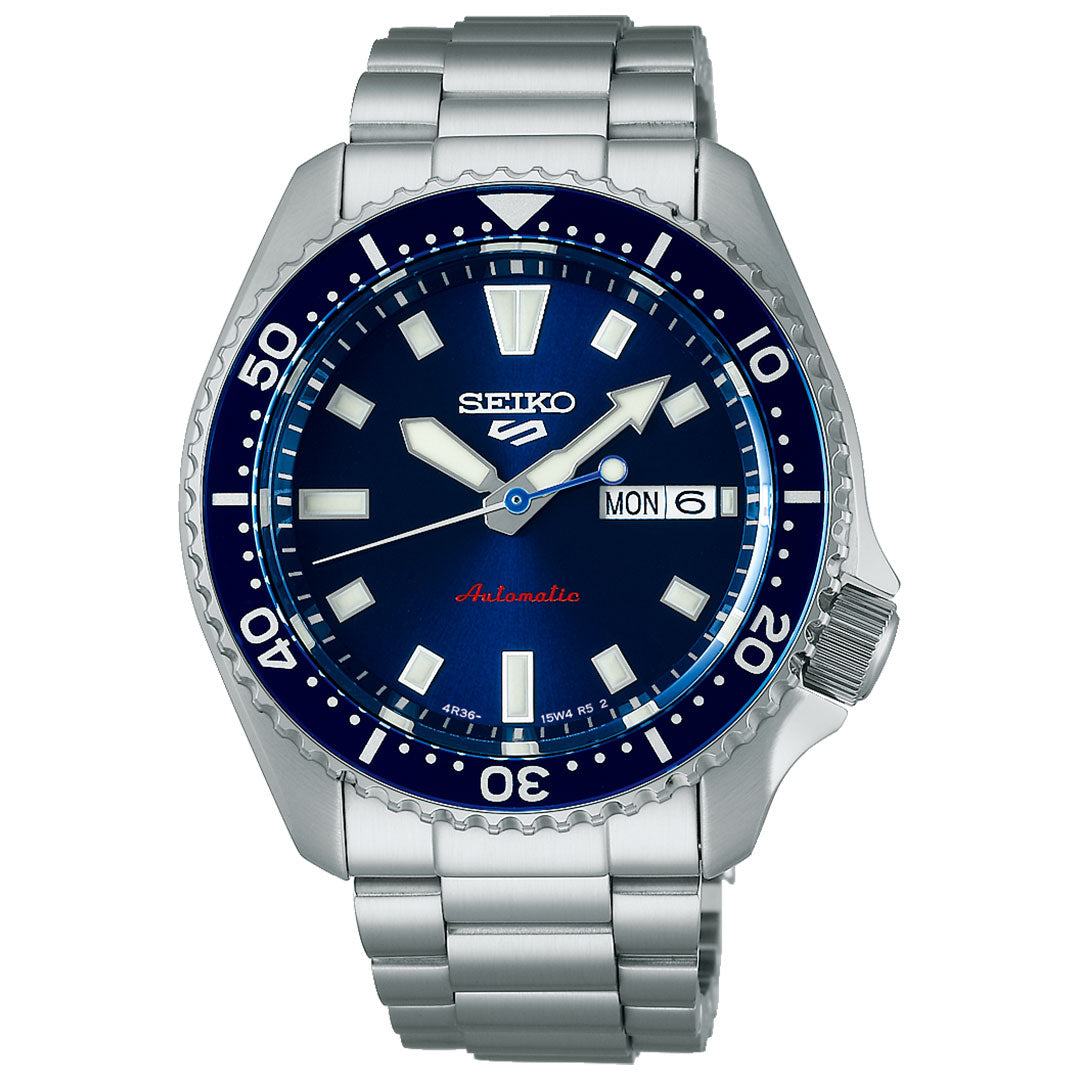 The Seiko 5 Sports SKX Series Automatic 42.5mm Watch features a blue sunray dial, white hour markers, silver hands, day-date display at 3 o’clock, rotating bezel, and a brushed stainless steel bracelet.