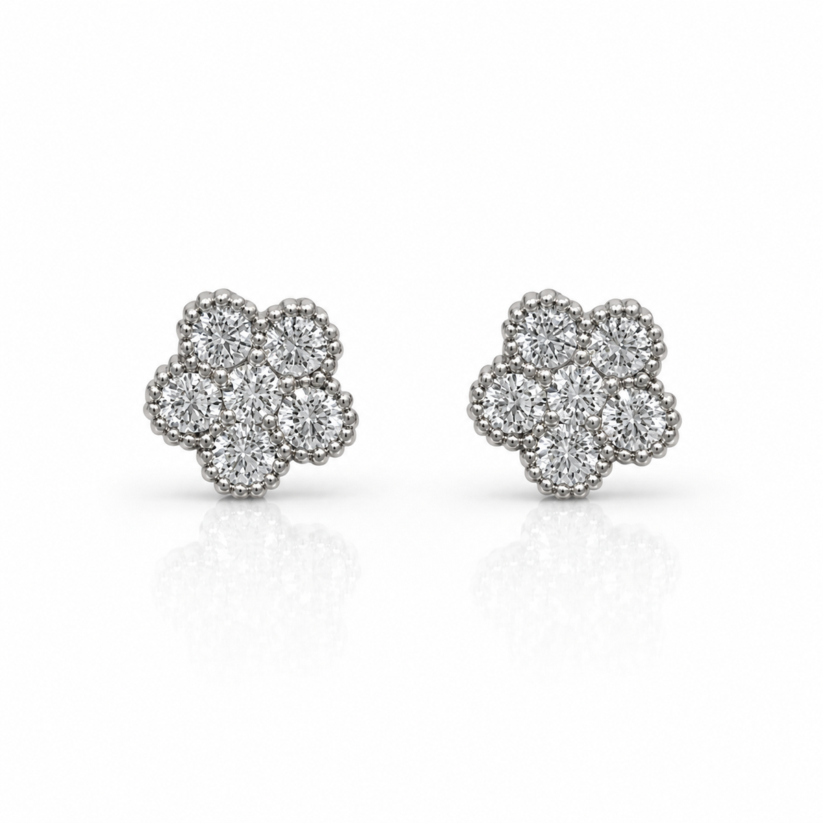 The Roberto Coin Tennis Flower 18K White Gold Diamond Stud Earrings feature six round diamonds in each floral-shaped earring, set in white gold with a beaded border, displayed on a white background with a subtle reflection.