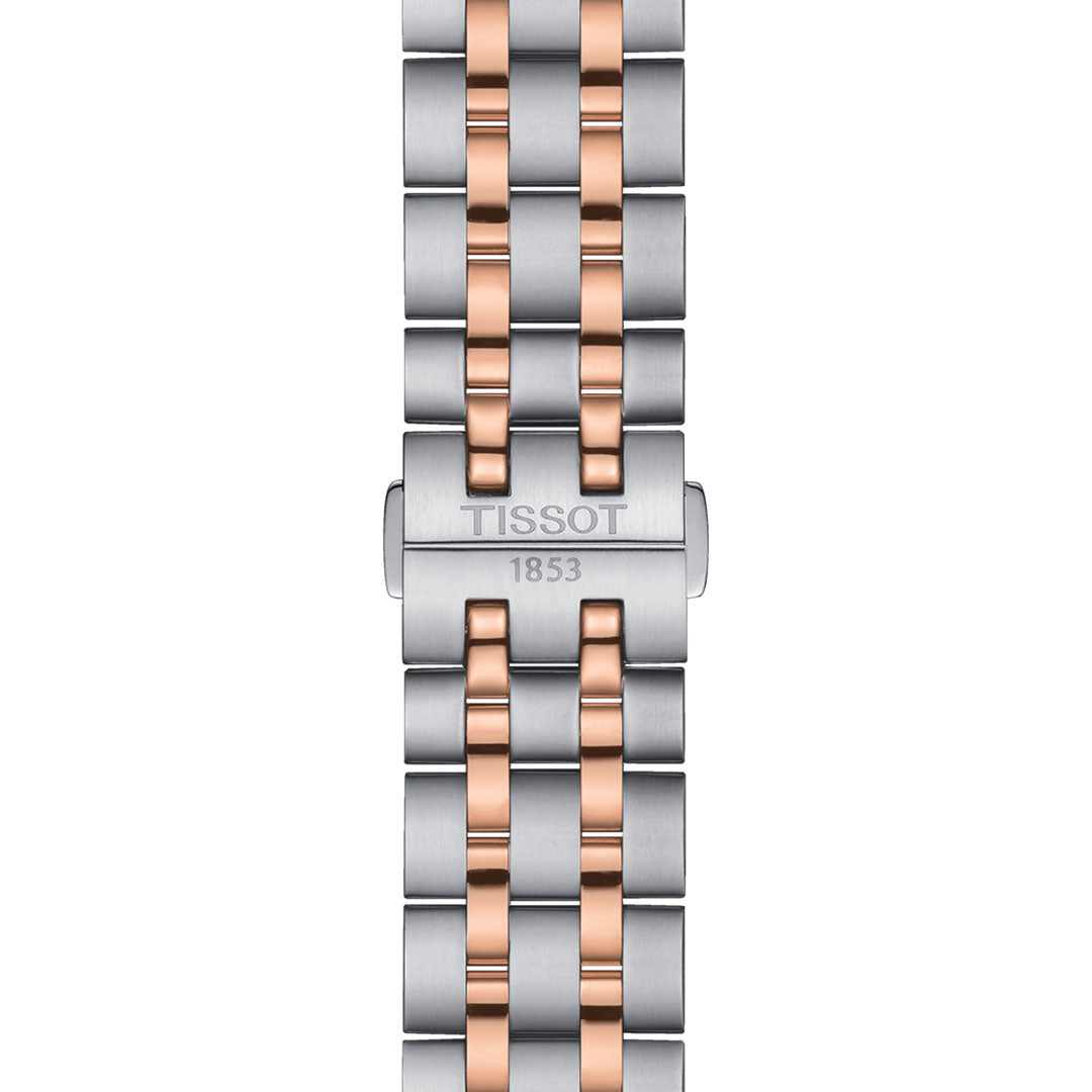 Close-up of the Tissot Classic Dream Quartz 42mm Watch band showcasing a mix of silver and rose gold PVD links. The clasp is engraved with the "Tissot" brand and the year "1853" below it. This sleek, modern design is enhanced by a sturdy stainless steel case.