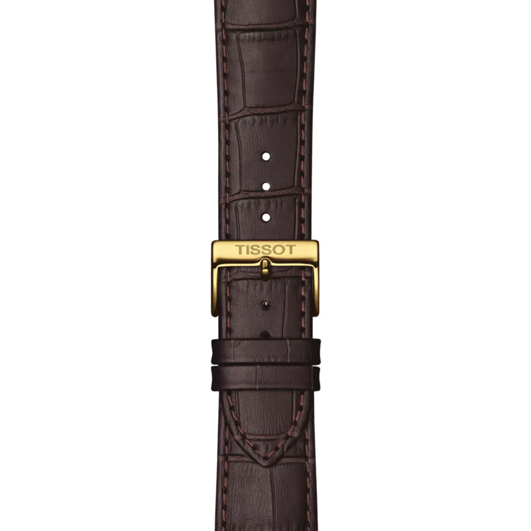 A close-up of a brown leather strap with crocodile pattern and gold Tissot-engraved buckle on the Tissot Classic Dream Quartz 42mm Watch, featuring visible stitching, adjustment holes, and a minimalist design.
