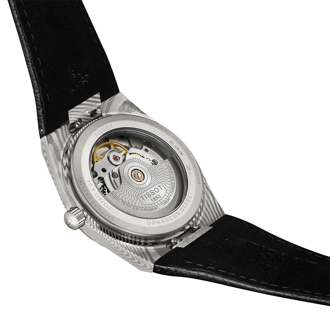 Close-up of the back of the Tissot PRX Damascus Steel Powermatic 80 Automatic 38mm Watch, featuring a marbled Damascus stainless-steel case, transparent case back revealing the movement and engraved details, and a black leather strap.