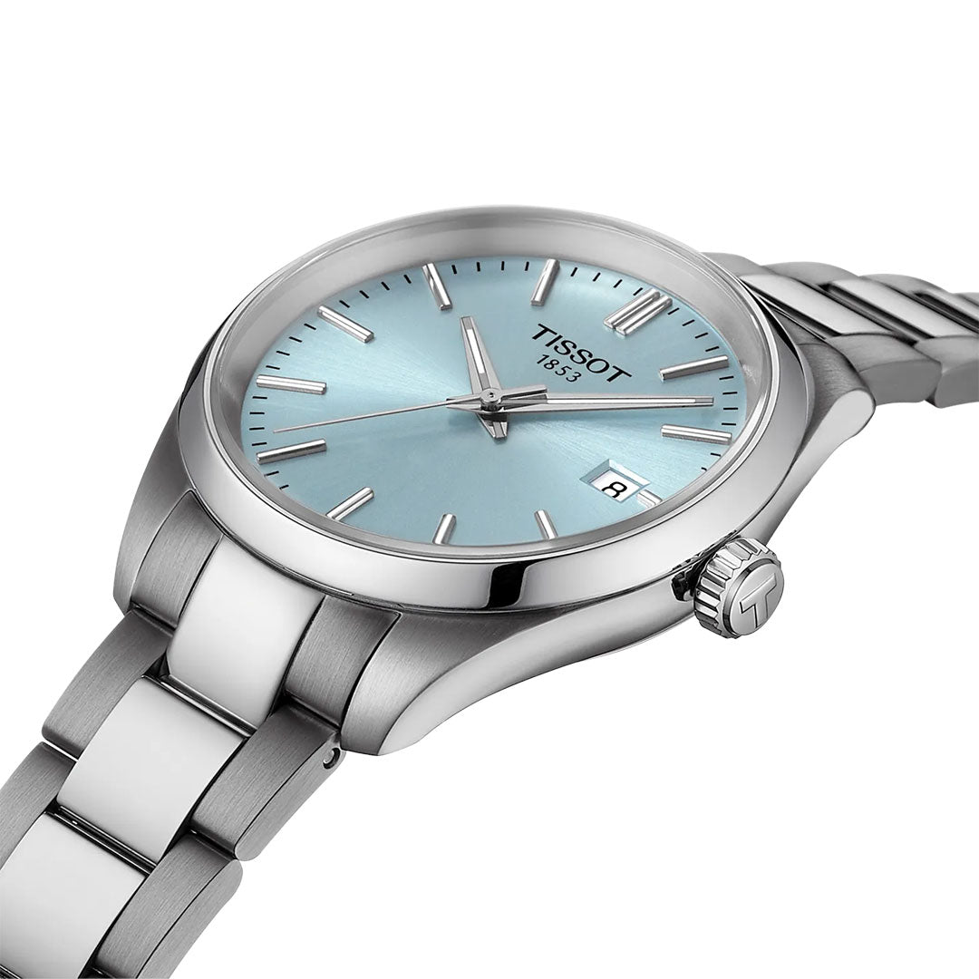 The Tissot PR100 Quartz 34mm Watch features a 316L stainless steel case, light blue dial with silver markers, Swiss Made quartz movement, and date at 3 o’clock. The watch is angled on a white background.