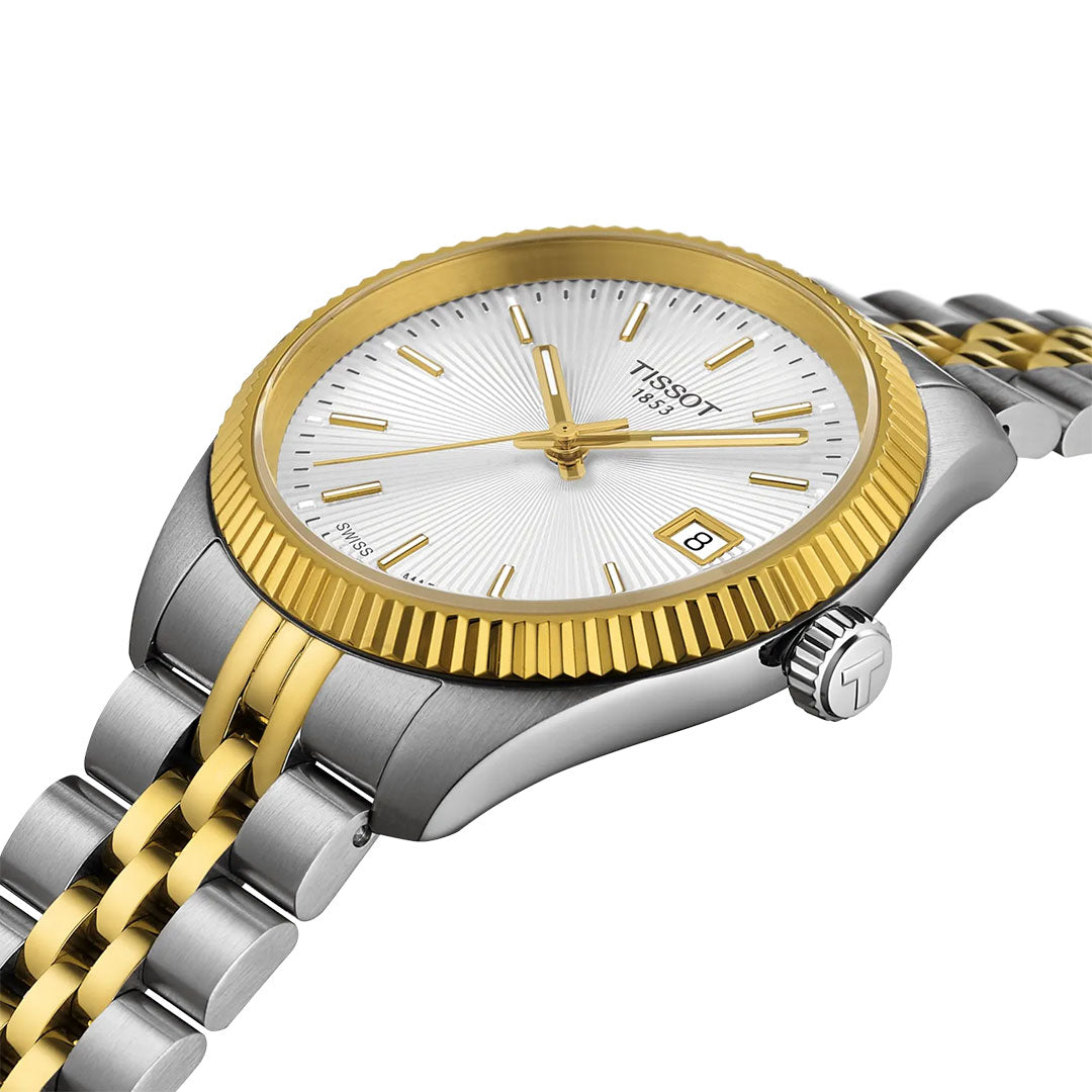 The Tissot Ballade Quartz 34mm Watch features a silver and gold metal band, round white guilloché dial, gold markers and hands, date window at 3 o’clock, fluted bezel, and a crown with the Tissot “T” logo.