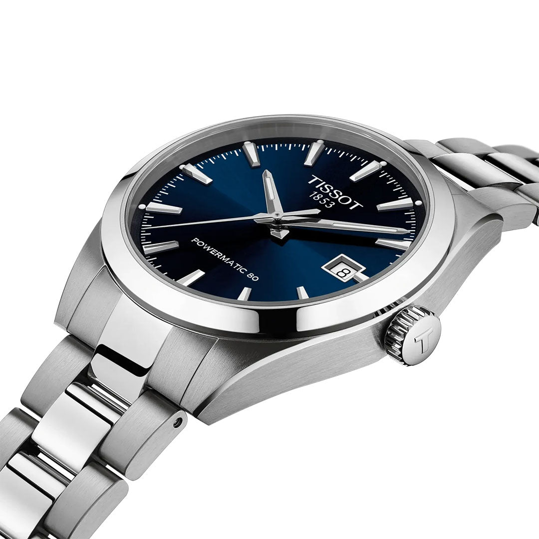 The Tissot Gentleman Powermatic 80 Automatic 38mm Watch features a blue dial with silver markers and hands, date window at 3 o’clock, polished stainless steel bracelet, and a crown engraved with the Tissot "T".