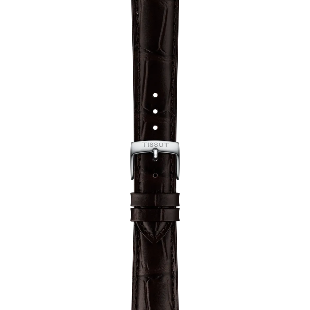 The Tissot Official Brown Leather Strap features an 18mm width and showcases a dark brown crocodile pattern with adjustable holes. It is finished with a silver buckle engraved "Tissot" and is displayed vertically against a plain white background.