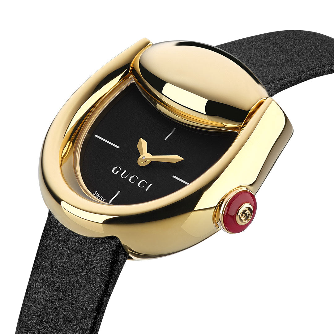 The GUCCI Horsebit Quartz 27mm x 25mm Watch features a black strap, yellow gold-plated asymmetrical case, minimalist black dial, gold hands, and a red Gucci-logo crown.