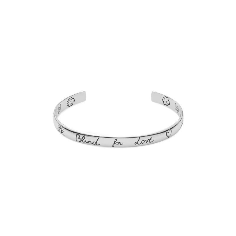 The Gucci Blind For Love Sterling Silver Cuff Bracelet, from GUCCI Fine Jewellery, showcases iconic Gucci motifs with decorative elements such as hearts and flowers, complemented by the endearing phrase "Blind for Love.