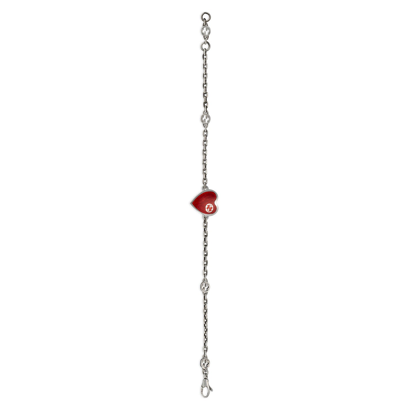 The Gucci Interlocking G Sterling Silver Station Bracelet by GUCCI Fine Jewellery highlights a red enamel heart pendant at its center, embellished with a white interlocking "G." The chain is crafted with decorative links and clasps at both ends, exuding elegance and charm in every detail.