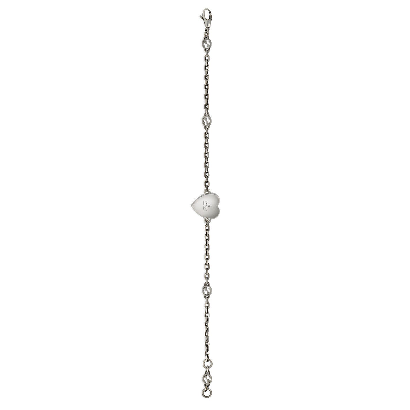 The Gucci Interlocking G Sterling Silver Station Bracelet by GUCCI Fine Jewellery showcases a central red enamel heart pendant with small bead accents along the chain. This elegant piece includes a lobster clasp closure and is beautifully presented against a white background, adding sophistication to any ensemble.