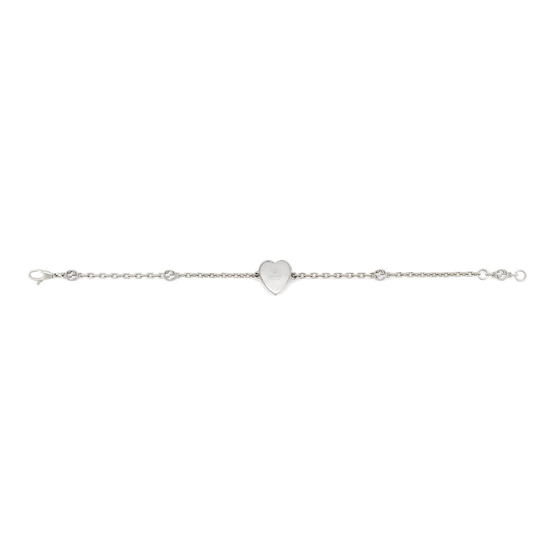 The Gucci Interlocking G Heart Enamel Sterling Silver Bracelet by GUCCI Fine Jewellery features a slender chain with small links and a central heart-shaped charm.