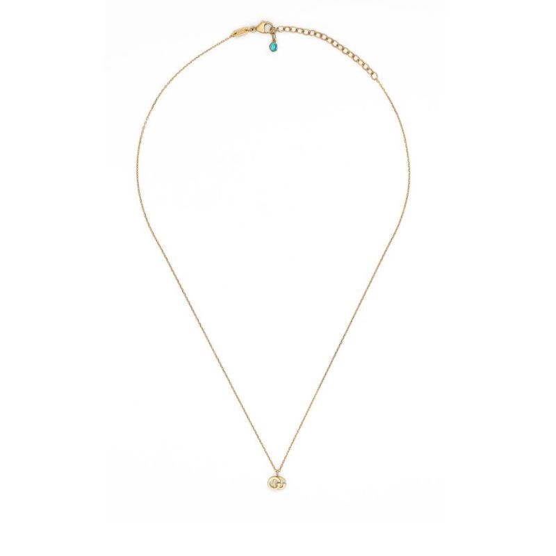 The GUCCI Fine Jewellery GG Running Necklace features a sophisticated 18K yellow gold design, highlighted by a dainty pendant showcasing the iconic Gucci emblem. The necklace is complete with an adjustable chain, accented by a blue bead at the clasp's end, and is displayed against a clean white backdrop.