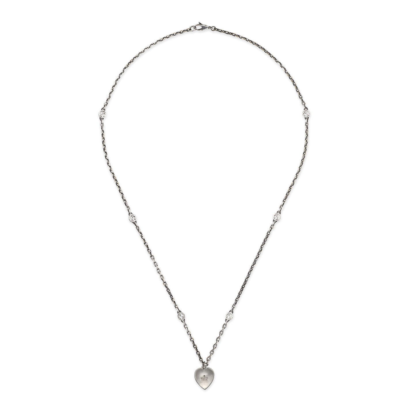The Gucci Interlocking G Sterling Steel Necklace with Red Enamel Heart Pendant by GUCCI Fine Jewellery features a delicate silver chain with small crystal embellishments, highlighting an elegant and minimalistic design. At its center is an Interlocking G pendant adorned with a red enamel heart, adding a touch of sophistication and style.