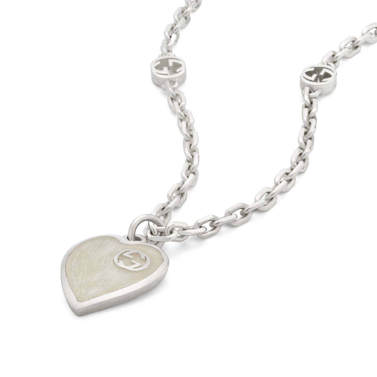 The Gucci Interlocking G Sterling Silver Heart Enamel Necklace Pendant by GUCCI Fine Jewellery features a silver necklace with an interlocking G heart pendant in mother of pearl enamel. The 925 sterling silver chain includes two circular links, each with a "G" logo, offering an elegantly minimalist design.