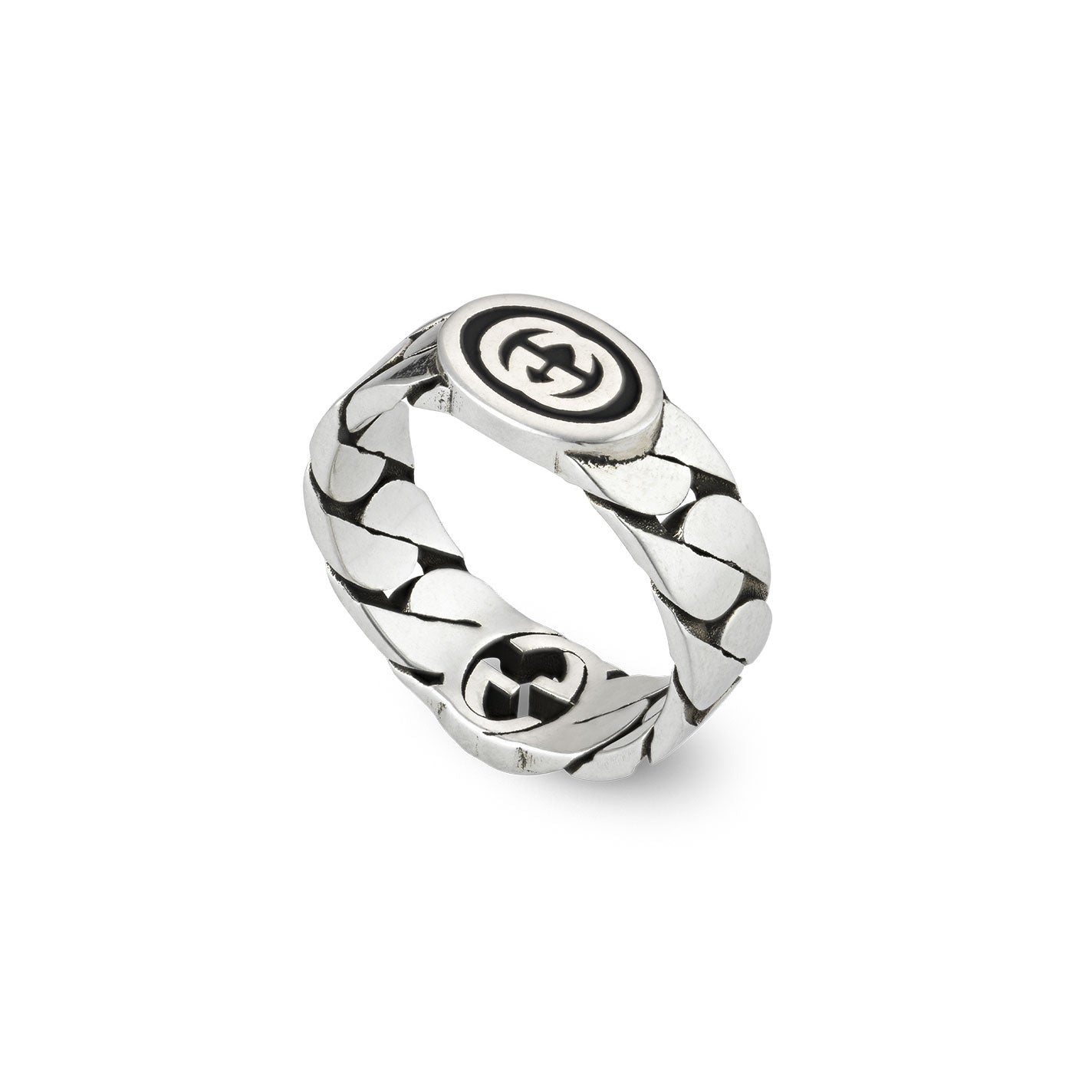 The Gucci Interlocking G Wide Sterling Silver Ring from GUCCI Fine Jewellery resembles a wide gourmette chain crafted from silver, adorned with a circular emblem showcasing interlocking geometric shapes. This intricate pattern, polished against a white background, embodies the elegance characteristic of the Gucci Aria Collection.