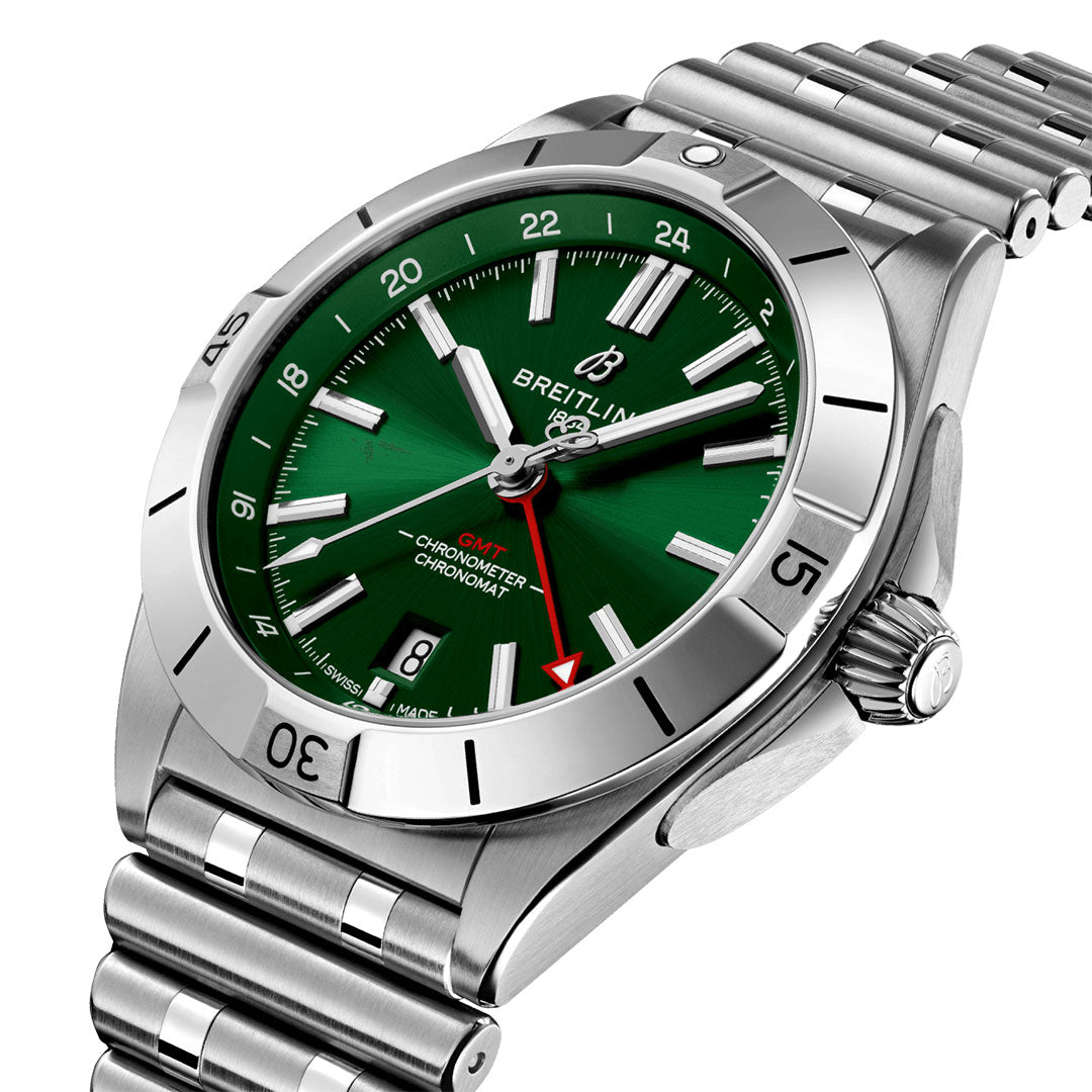The BREITLING Chronomat Automatic GMT 40 is a silver watch featuring a green dial with the ability to track dual time zones. It includes a metal band, prominent hour markers, and a rotating bezel, all powered by the Breitling Caliber 32. The silver hands are accentuated by a distinctive red-tipped second hand and display the Breitling brand name clearly on the dial.