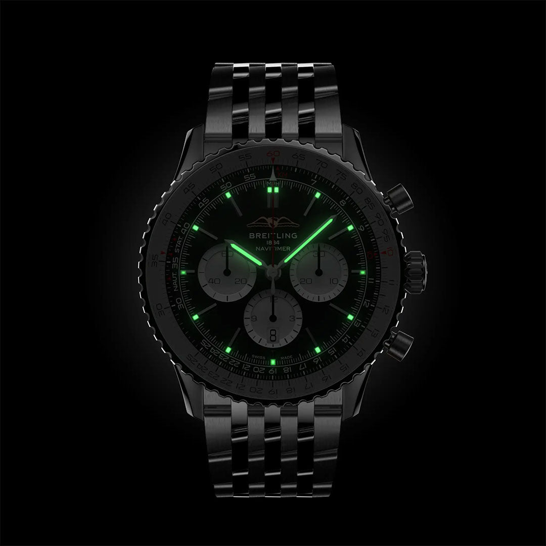The Breitling Navitimer B01 Chronograph 46 features a luminous black dial with green markers, glowing hands, three lit subdials, and a striking metal bracelet—highlighting this iconic aviation watch from Breitling.