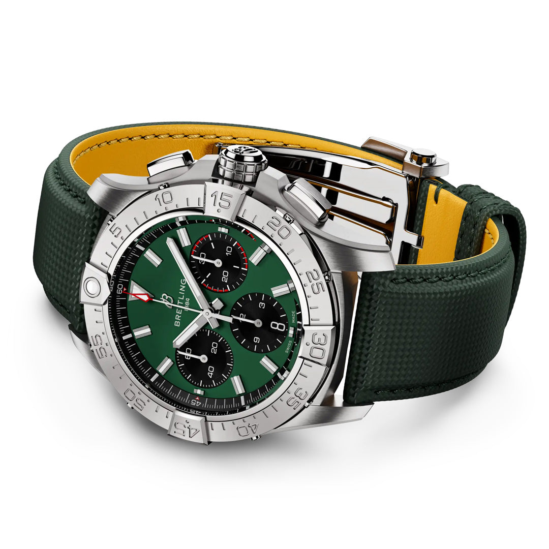 Displayed is the BREITLING Avenger B01 Chronograph 42, a luxury wristwatch with an aviation theme. It has a green dial with three subdials, stainless steel case, and an Avenger-inspired dark green textured leather strap with yellow lining and buckle clasp on a pristine white background.
