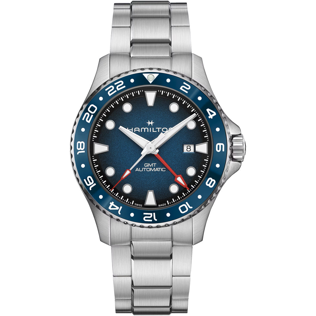 The Hamilton Khaki Navy Scuba Auto GMT 43mm Watch features a blue dial, blue and red bezel, silver markers, date at 3 o’clock, silver bracelet, automatic movement, 300m water resistance, and “GMT”/“Automatic” on the dial.