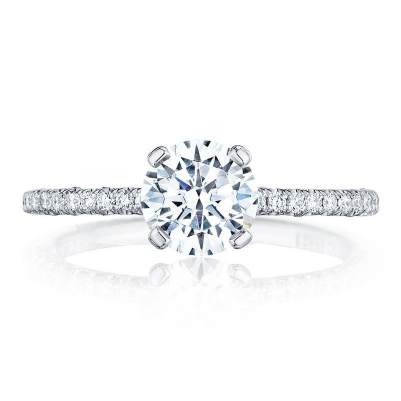 The Tacori Petite Crescent 18K White Gold Round Brilliant Solitaire Semi Mount with Diamond Band Engagement Ring highlights a large round-cut center diamond, accompanied by smaller diamonds in the Petite Crescent arrangement along the band. This stunning engagement ring is displayed against a plain white backdrop, emphasizing its brilliance and detailed craftsmanship.