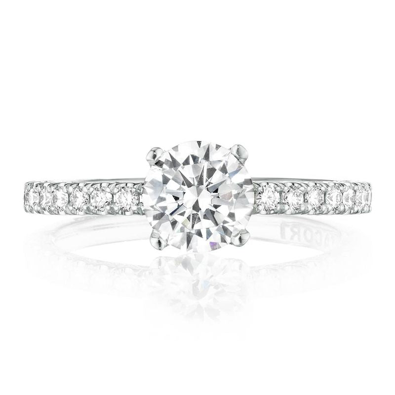 An elegant Tacori Petite Crescent engagement ring, crafted in 18K white gold, showcases a stunning round-cut center stone on a slender band. The ring is adorned with small round diamonds along the diamond-studded band, and its brilliance is captured against a white background.