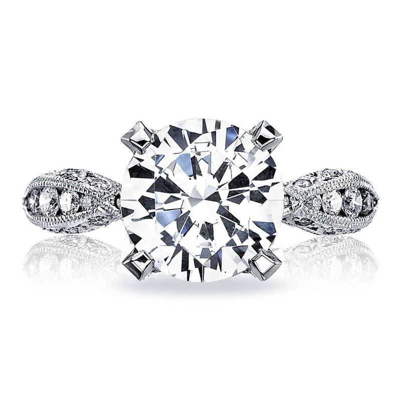 The Tacori Classic Crescent RoyalT Platinum round brilliant solitaire semi mount engagement ring showcases a large round central diamond, surrounded by smaller G color diamonds set in an ornate band design.