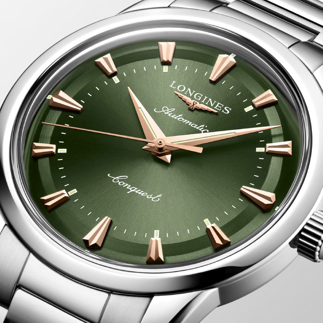 A close-up of the Longines Conquest Heritage Automatic 40mm Watch, featuring a green sunray dial, gold-tone markers and hands, and a silver stainless steel bracelet—combining vintage style with modern craftsmanship.