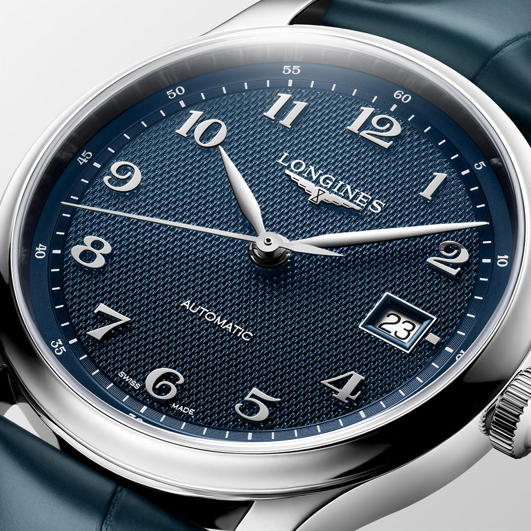 Close-up of the Longines Master Collection Automatic 39mm Watch, featuring a textured blue dial with silver hour markers and hands, a date window at 3 o’clock, and a blue leather strap. This luxury timepiece from Longines proudly displays “Automatic,” showcasing the brand’s renowned horological craftsmanship.